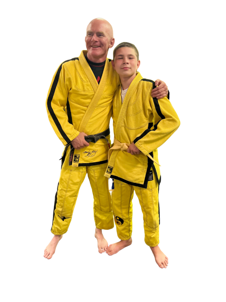 Chris (owner of Gracie Jiu Jitsu) posing with a student. Both wearing yellow jiu jitsu kimonos.